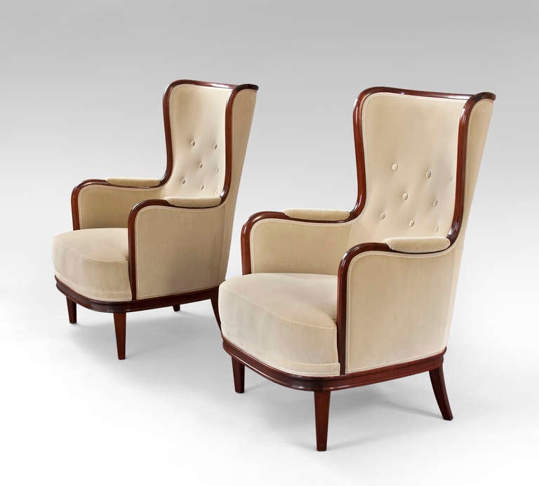 Boldly proportioned with a generously scaled seat, a rare and most likely, a bespoke model.  Each with upholstered backs, surmounted by a molded concave toprail, flowing continuously down through each armrest, the seat above a molded apron, on