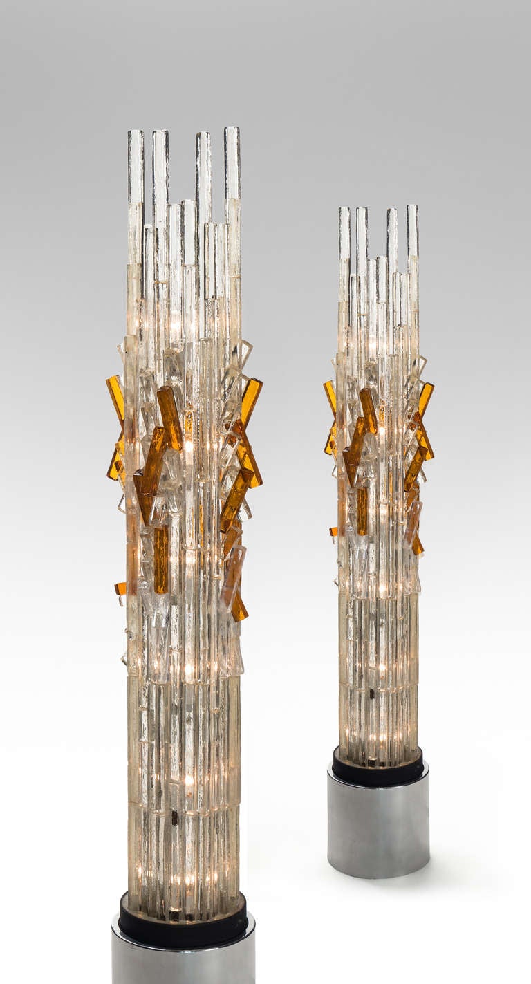 The colorless glass blocks forming a cylindrical diffuser, the center highlighted by angular amber colored glass rods, the stacked top dominated by four glass rods thrusting skyward, the whole raised on a chrome cylinder.