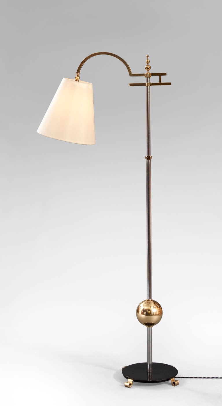 The cylindrical standard adjustable for height, surmounted by a three-tier spherical finial, issuing an arched arm with a conical shade, above a large brass sphere and circular base, terminating in scrolled feet. 

More lighting also available at: