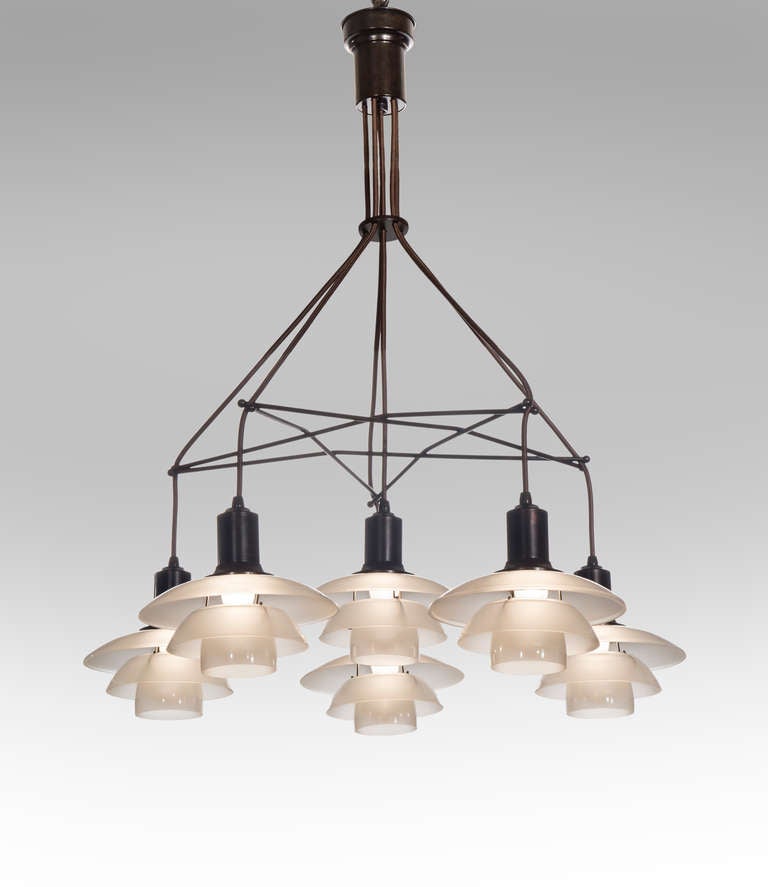 One of lighting innovator Poul Henningsen's most appealing and sought after designs. The molded cylindrical canopy, issuing six cords threaded through a star-shaped metal frame, each cord terminating in a PH 2/2 shade-set of frosted glass, each