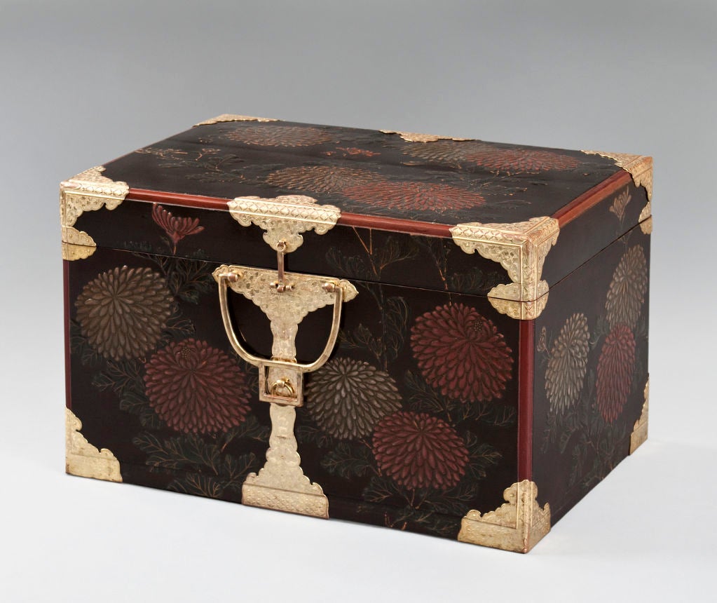 The whole hasami bako (robe chest) adorned in bold red and silver chrysanthemum blossoms in the Rimpa School manner, the gilt copper mounts engraved with trailing vines, fitted with loop handles.  <br />
<br />
Now on later, removable stand. 