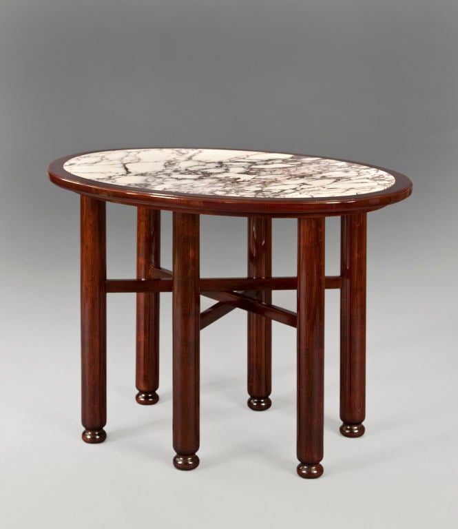 The oval top of brecica marble inset into a conforming molded edge, above six cylindrical legs joined by three overlapping stretchers, on bun feet. <br />
<br />
The same model table in the Vienna residence of Wohnung Valentin Rosenfeld from 1912