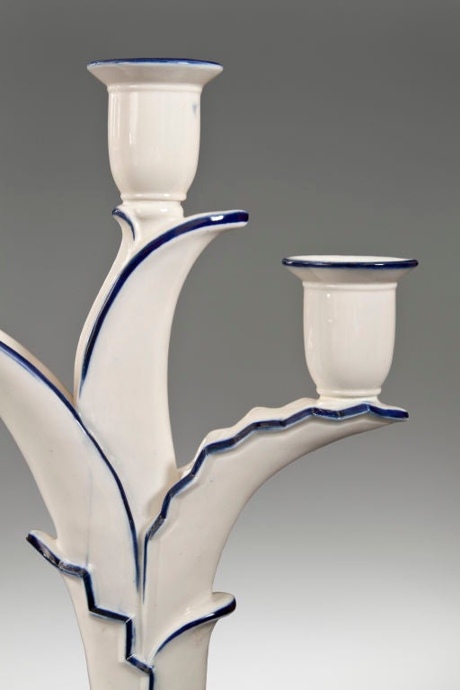 Each in the form of a plant with unfurling leaves, issuing three candle holders, on a molded oval base with two stylized bracket feet. Each stamped: Schwarzburg Werkstätten Für Porzellankunst 2337<br />
<br />
Provenance:  A private Swiss