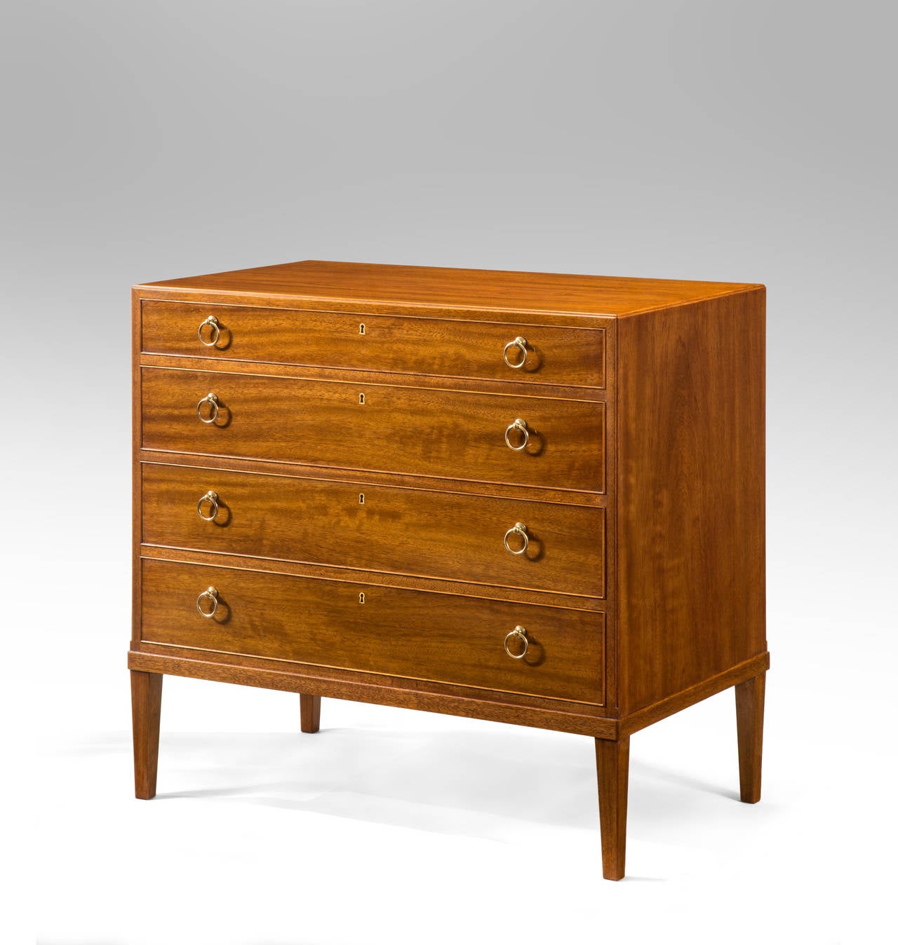 The rectangular top above 4 graduated drawers with brass ring pulls, raised on square tapering legs.