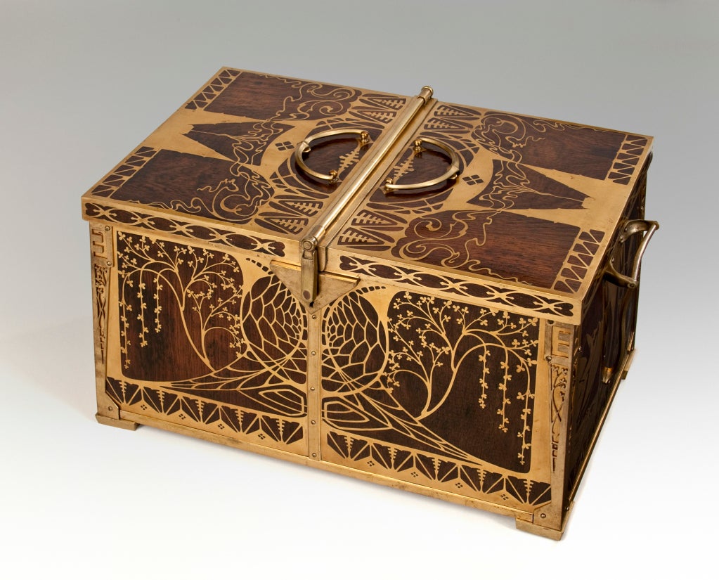 The rectangular lid with naturalistic tendril inlay, opening centrally with locking mechanisms on each side, over a conforming base centering two curvaceous handles and adorned in inlay depicting four different scenes: three landscapes and one