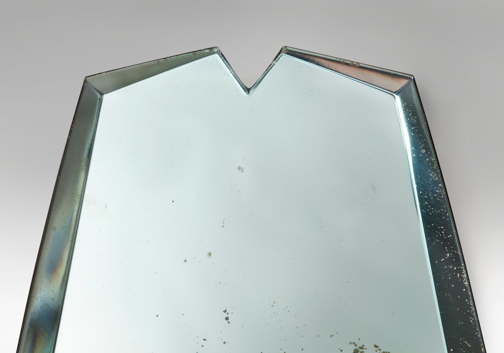 The cartouch-shaped aquamarine-tinted mirror plate with an angular bevel, issuing four curvaceous upright brass arms, each arm with a single light holder.

For related examples see Pierre-Emmanuel Martin-Vivier, Max Ingrand Du Verre à la Lumière,