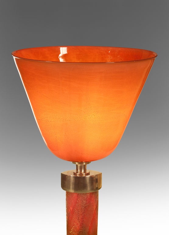 The gold flecked, layered and richly colored conical laguna glass bowl, above an elliptical glass standard, terminating in a conforming brass base. Marked: Venini Murano. 

This lamp was displayed at the Tomaso Buzzi at Venini exhibition,