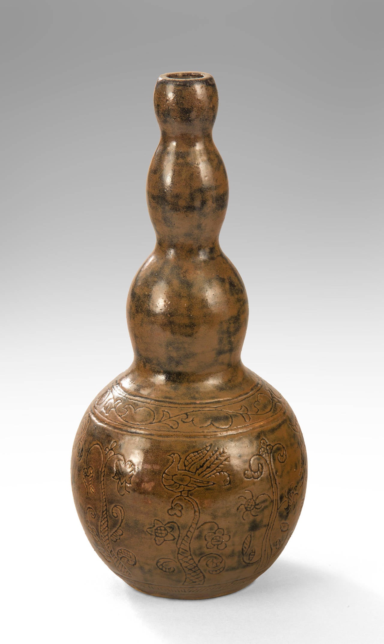 The quadruple gourd form, incised with reliefs depicting flowers and a bird, terminating in a circular base, glazed throughout with rich browns and charcoal.

Seraphin Soudbinine, sculptor, painter and ceramicist born in Russia, worked much of life