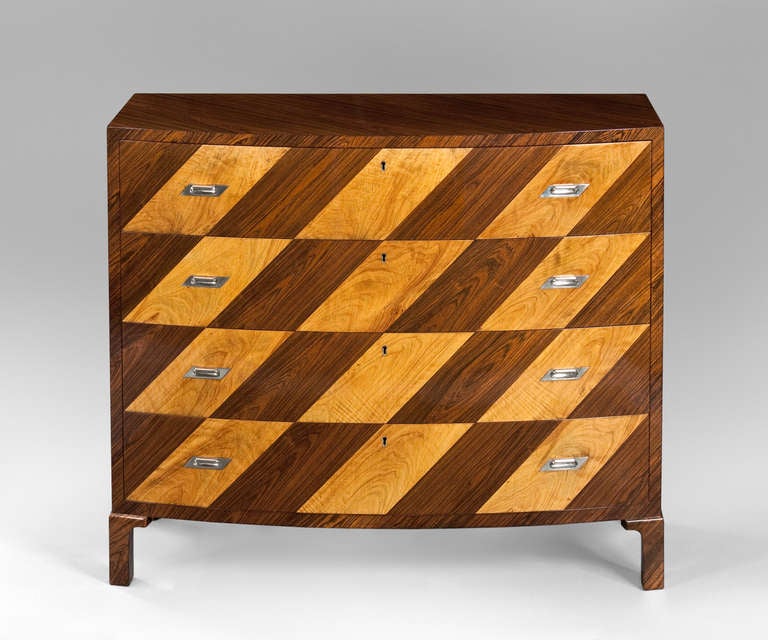 The rectangular top with convex front, above four conforming drawers in rhomboid rosewood and maple marquetry, each drawer with two rhomboid shaped cast nickeled-bronze pulls centering a keyhole, terminating in four stylized feet. 

The Bergsten