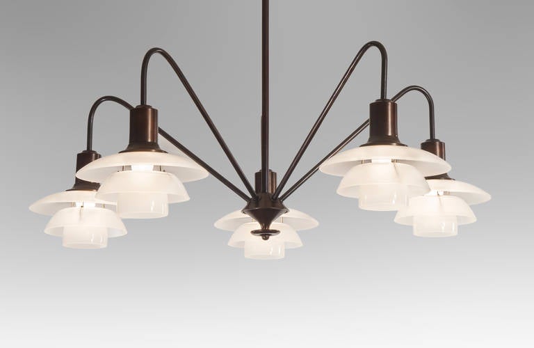 The circular corona, above a central hanging rod, the inverted bronze bowl and finial issuing five angled arms, each suspending a 2/2 frosted glass shade set. Marked: PHLamps Patented
The height can easily be adjusted. 
Overall height: 30