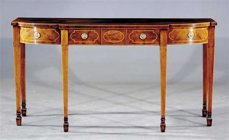 A George III mahogany breakfront serving table, the breakfront strung with boxwood, having three drawers with boxwood stringing over square tapered legs with spade feet.
