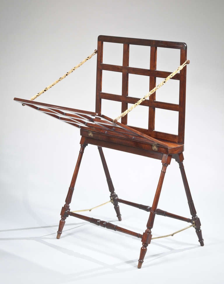 A Regency folding folio stand of solid rosewood with carved and turned stylized acanthus leaf decoration on the legs.