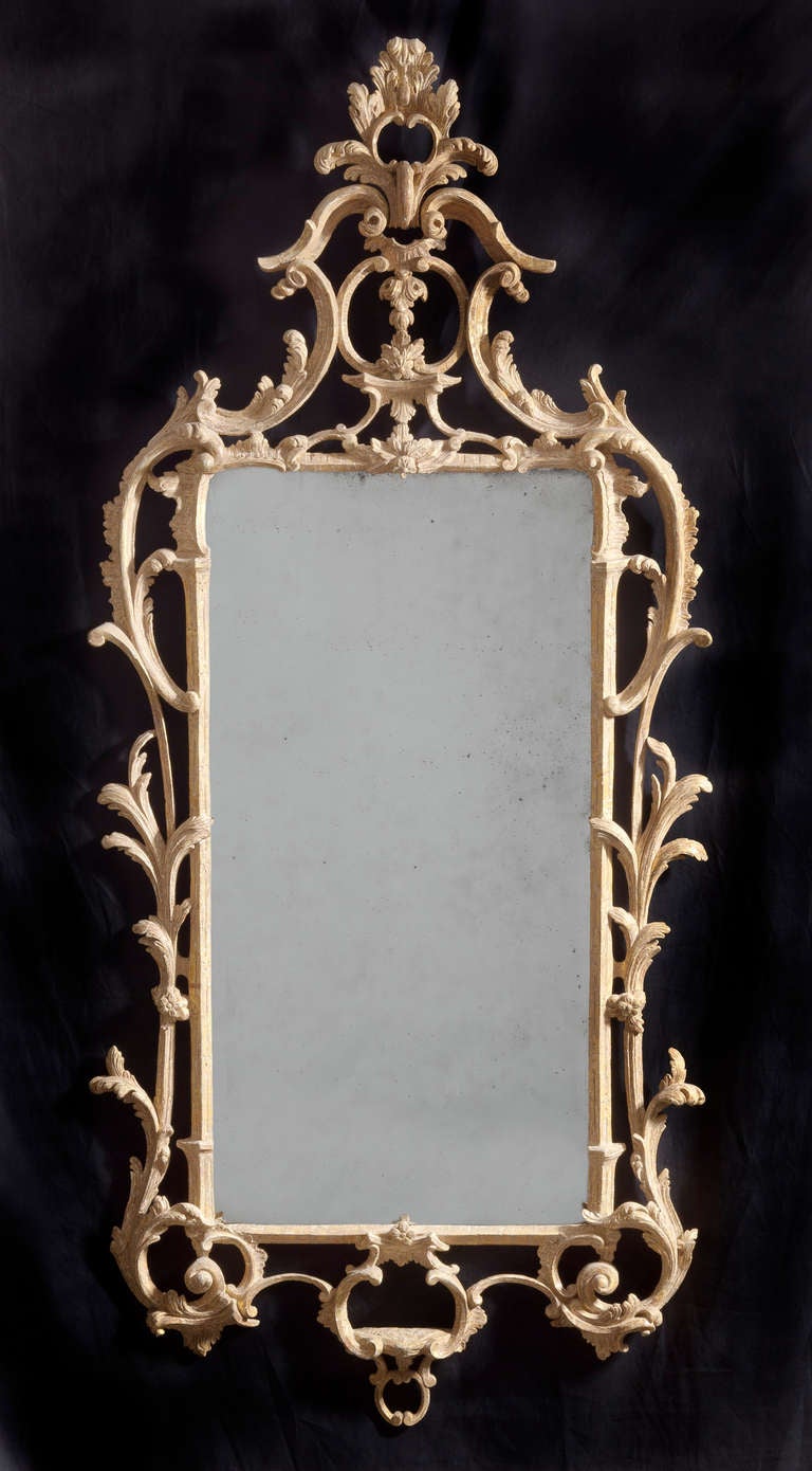 A fine rococo giltwood mirror with original beveled glass plate, dry stripped to its original gilding. Some replaced carvings and retouching to the gilding. 
H: 67 ¼”, W: 28 ¾”