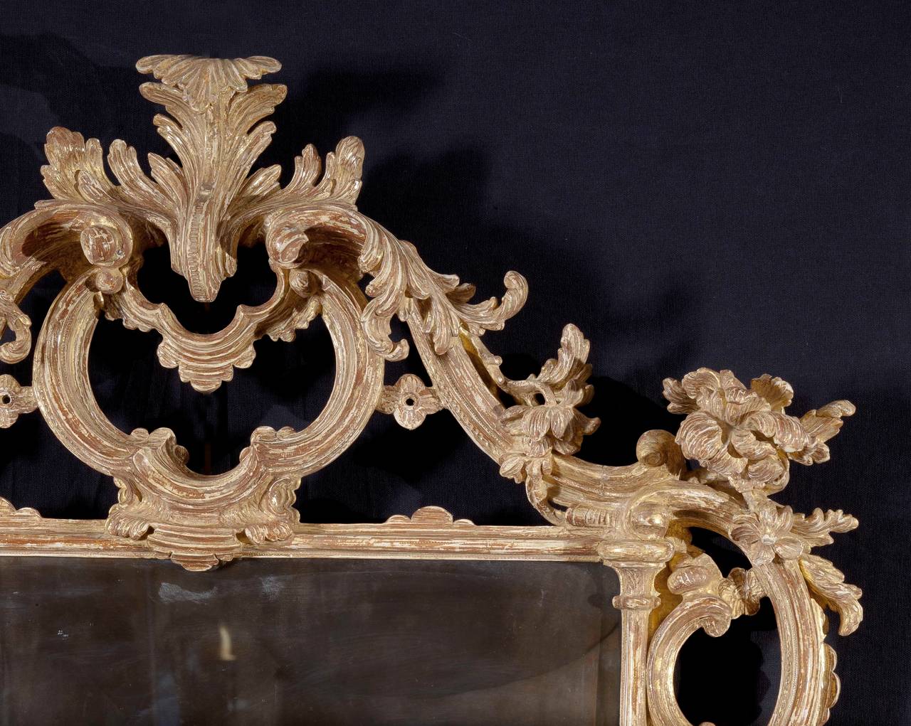 A carved beechwood rectangular rococo mirror with re-silvered original glass, and a finely carved and detailed frame, which is crested with a scrolled acanthus leaf resting on double C-scrolls with C-scrolls bracketing the sides of the frame, having