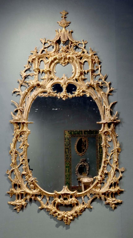 An exceptional English rococo carved and gilded mirror frame in the style of Thomas Johnson, the inner frame in the form of a cabochon created of double c-scrolls flanked by pagodas on either side and a pagoda at the base, the outer frame consisting