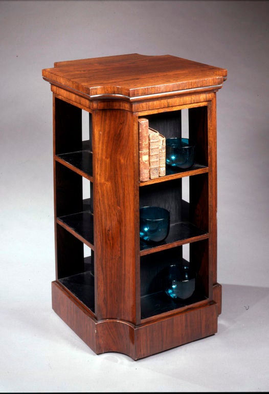 A four-sided Regency veneered rosewood set of shelves with inset quarter round corners set on a plinth base.