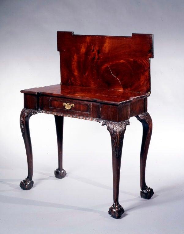 A fine mahogany tea table with outset corners,  a frieze with a central drawer and carved cabriole legs with ball and claw feet.