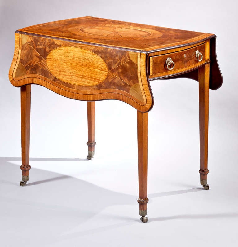 A George III mahogany pembroke table inlaid on the butterfly shaped top with a central boxwood paterae banded with satinwood and tulipwood and surrounded by boxwood and ebony stringing, the faded crotch mahogany divided by stringing into eight