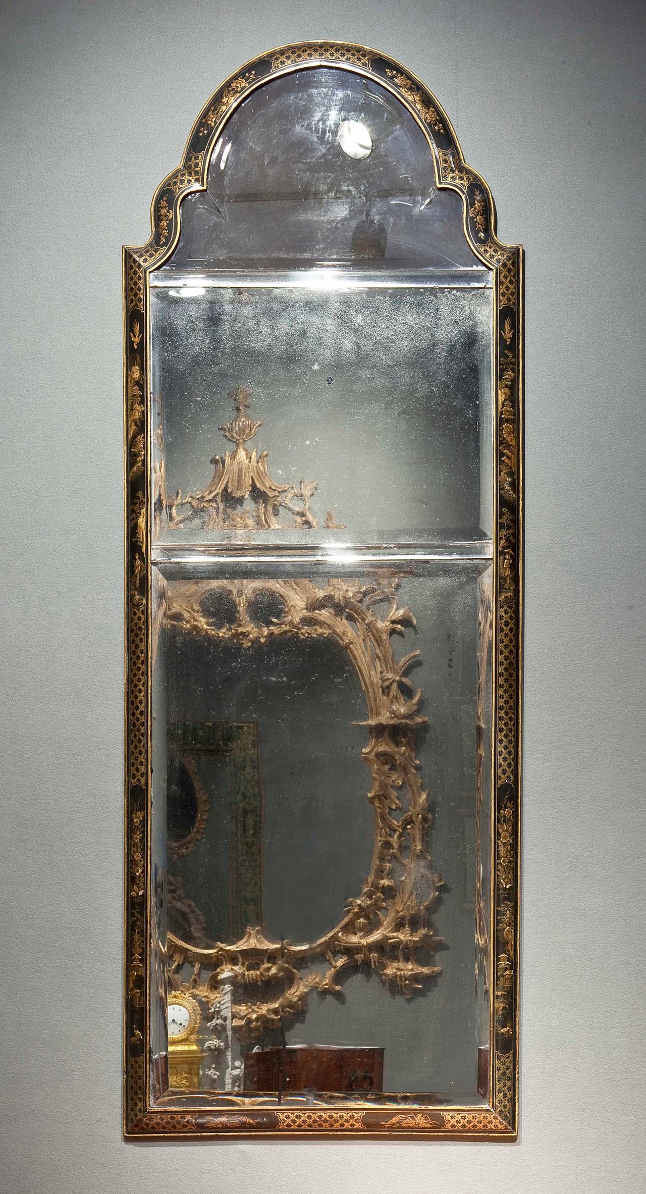 An elegant japanned chinoiserie mirror with an arched top and cushion frame with a bead around the exterior, having three re-silvered but original major beveled glass plates with two beveled glass bars separating the plates, touch-ups to decoration.