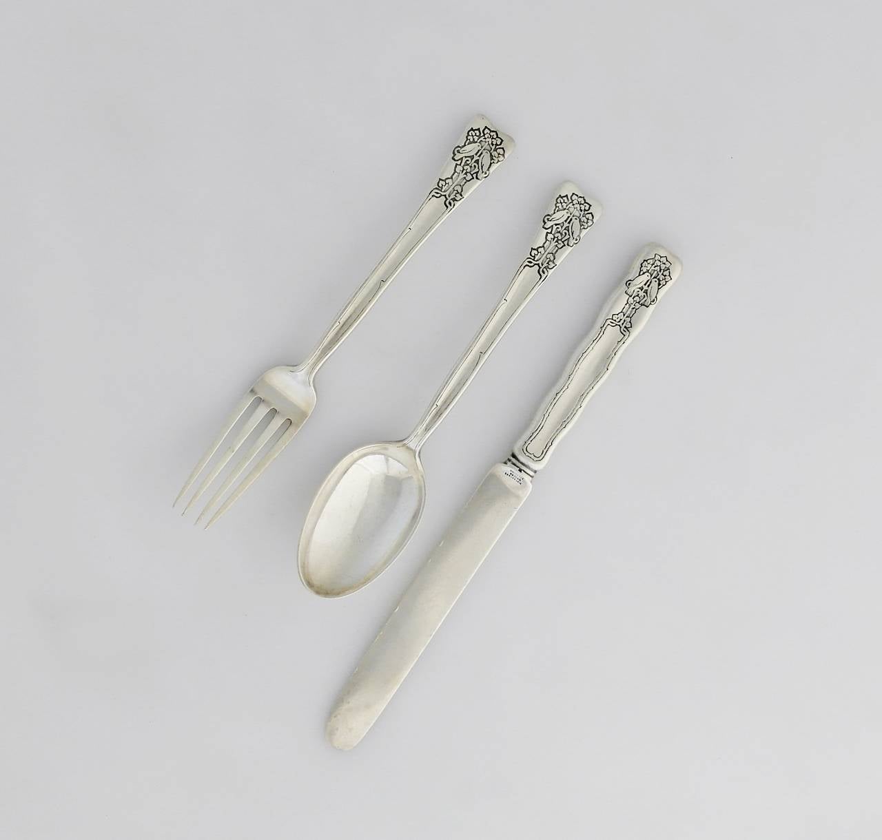 Being offered is a circa 1890 set of three child's flatware pieces by Tiffany & Co. of New York, New York. In the Lap Over Edge pattern, comprising a child's fork, spoon and knife adorned with birds surrounded by foliage. Dimensions:  knife 8 1/2
