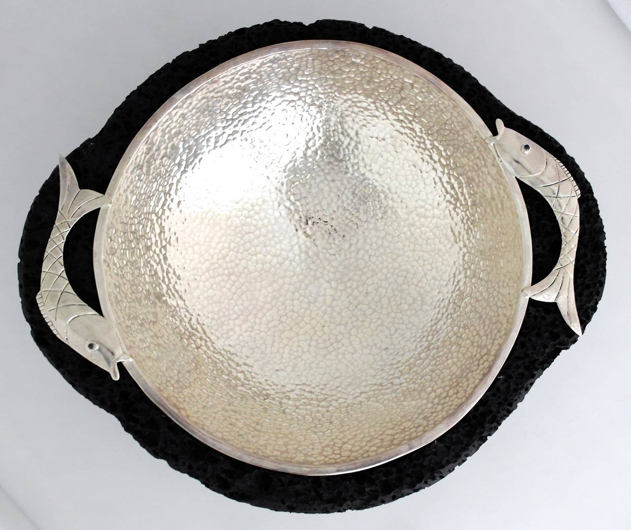 Being offered is a circa 1990 silver bowl by Emilia Castillo of Taxco, Mexico. Hand hammered bowl with fish motifs, resting on lava rock. Silver bowl is removable for cleaning. Dimensions: 14 inches diameter. Marked as illustrated. In excellent