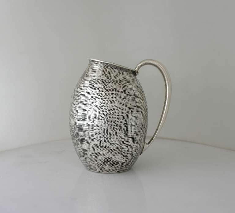 Being offered is a circa 1950 sterling silver water pitcher by Tane of Mexico City, with elegant, irregular lipped and bulbous shaped, the entire surface hand textured in a faux shagreen effect.  Dimensions  8 inches high, 6 inches over handle.  
