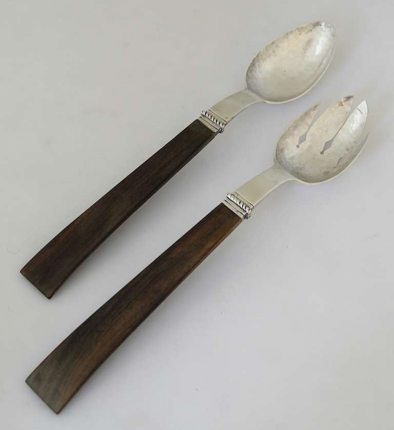 Being offered are a circa 1940 pair of sterling silver & rosewood salad servers by William Spratling of Taxco, Mexico, made during his first design period (1931-1946), comprising hand wrought serving ends with an applied rope motif at neck; attached