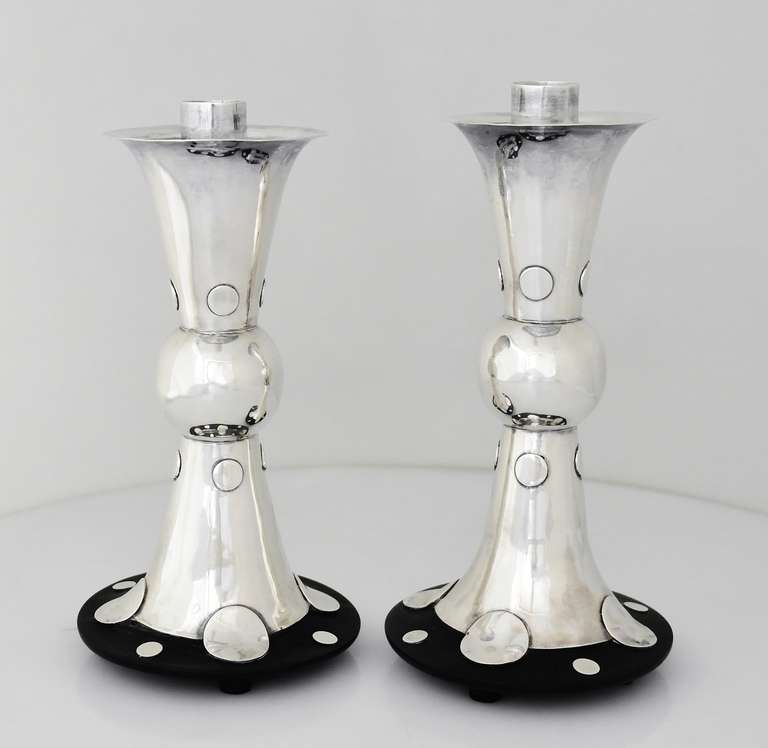Being offered are a pair of circa 1960 sterling silver and rosewood candlesticks by William Spratling of Taxco, Mexico, of baluster form on rosewood bases, set with circular silver bosses, featuring applied silver disks. Height 8 1/2 inches. Marked.