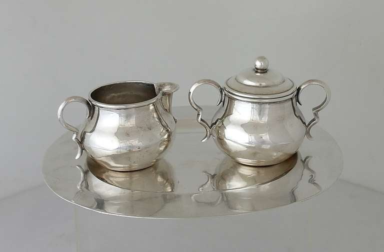Being offered is a rare circa 1930s sterling silver sugar, creamer and tray by William Spratling of Taxco, Mexico, made during his first design period (1931-1946), hand-wrought pieces, bulbous shaped with scroll handles, including a scarce hand made