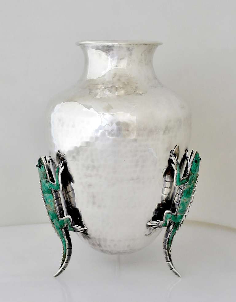 Being offered is a circa 1999 silver plate vase by Emilia Castillo of Taxco, Mexico. Bulbous shaped vase with hammered texture, raised by three figural iguanas with azurite stone inlay; incredible detail on each iguana. Dimensions: 10