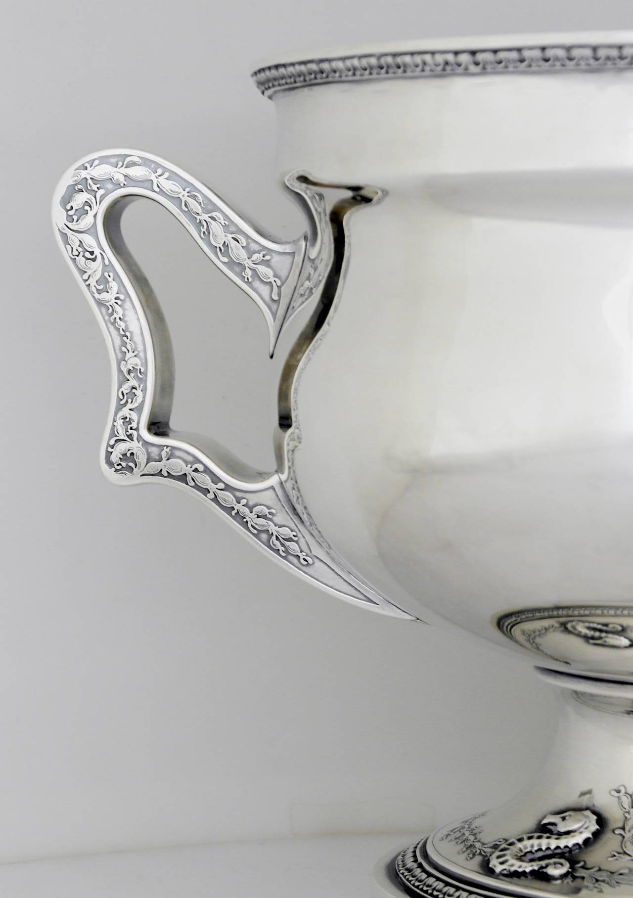 Being offered is a, circa 1912 sterling silver wine bucket by Gorham of Providence, Rhode Island. Comprising a bulbous form bowl with wide engraved handles at opposite ends, pedestal base decorated with four seahorse motifs, floral seaweed