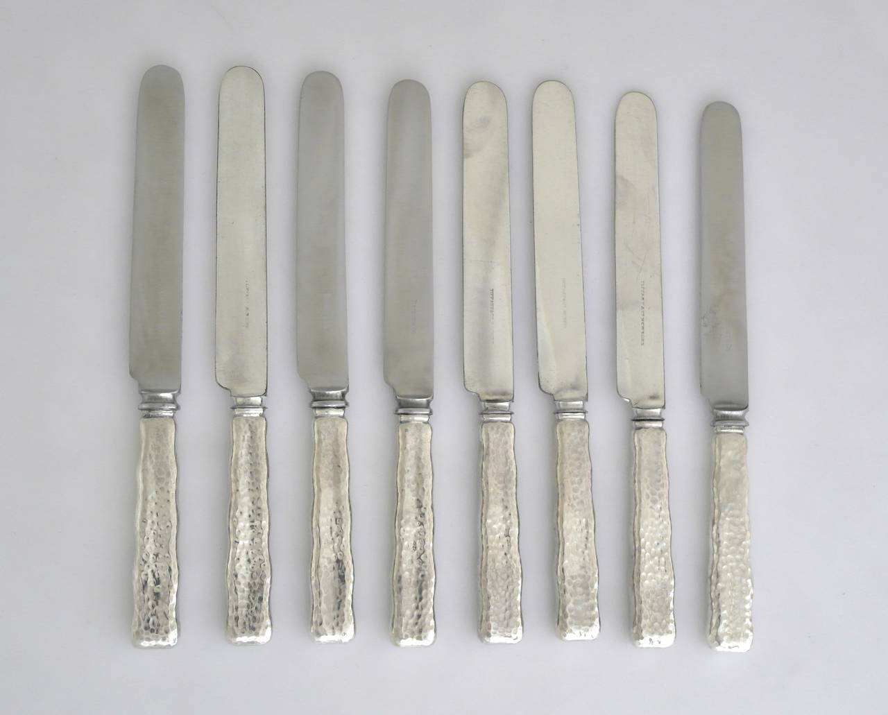 Being offered are a circa 1880 sterling silver set of eight dinner knives by Tiffany of New York, in the lap over edge hammered pattern. 
More pieces are available in this pattern, including the luncheon knives. 
Dimensions: 10 1/4 inches. Marked