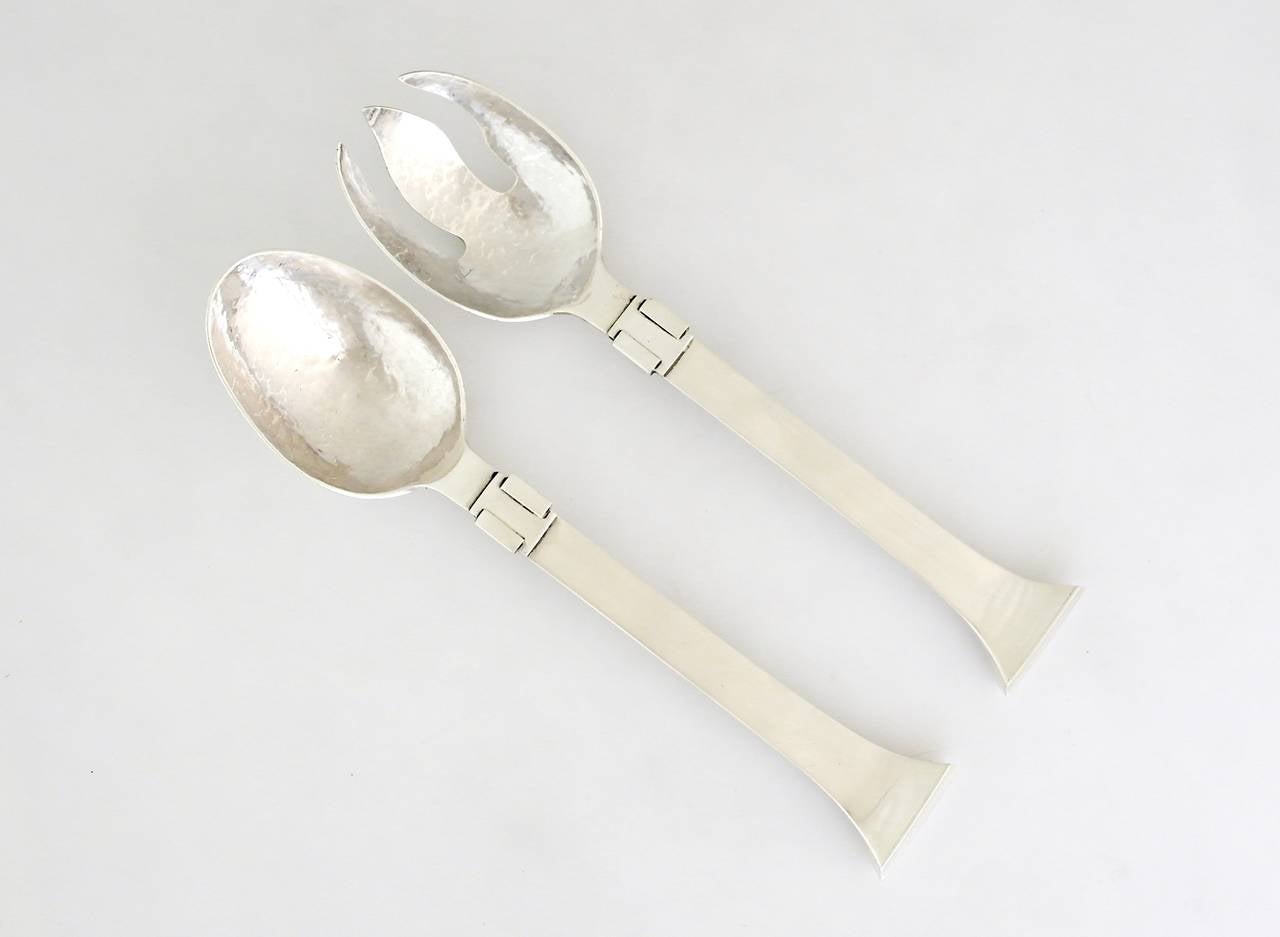 Being offered is a sterling silver salad set by Antonio Pineda of Taxco, Mexico; of modernist taste, hand-hammered bowl and tines extending to a tapering handle. An applied silver band near the serving ends are the primary decorative element.