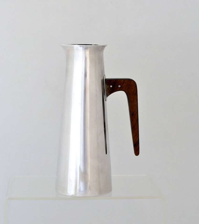 Being offered is a circa 1960 sterling silver pitcher by Californian Paul Pancritius. Of modernist form with a tapered cylindrical body & angular wood handle. Dimensions: 6 3/4