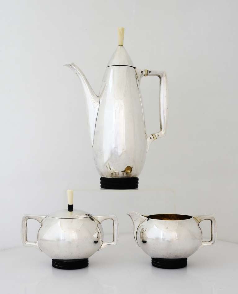 Being offered is a circa 1950 sterling silver coffee set by Los Angeles, California based Mesick Mfg. Co. The ovoid coffee pot and spherical sugar & creamer with angular handles, raised on reeded wood bases. Dimensions: Coffee pot - 10 1/2