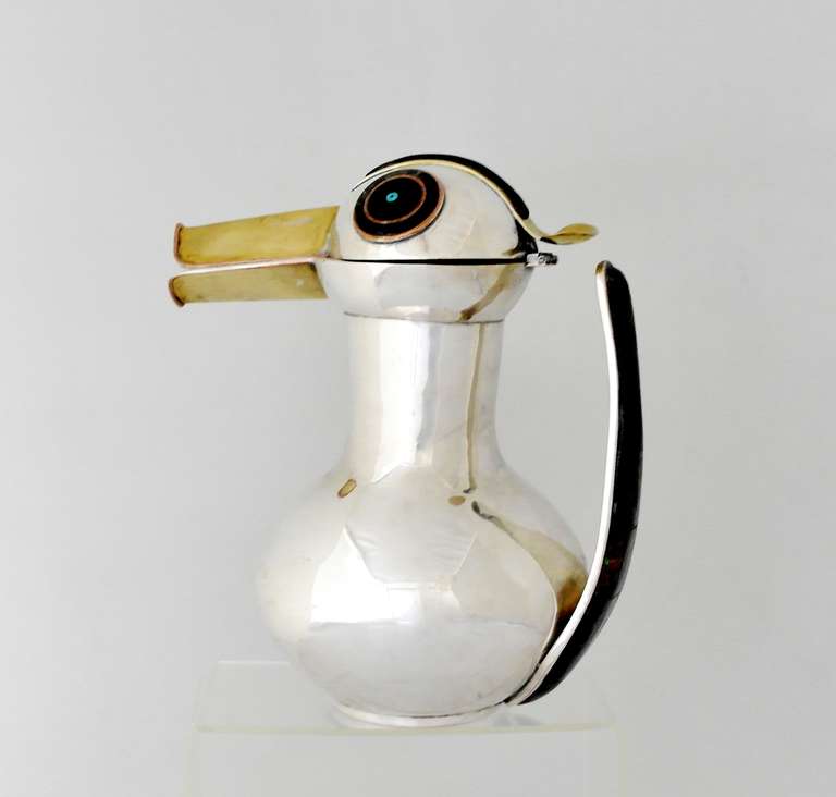 Being offered is a contemporary silverplate pitcher by Los Castillo of Taxco, Mexico. Entirely handmade piece in the form of a bird with a long brass bill & detailed circular eyes adorned with natural stone inlay & copper bands; handle decorated