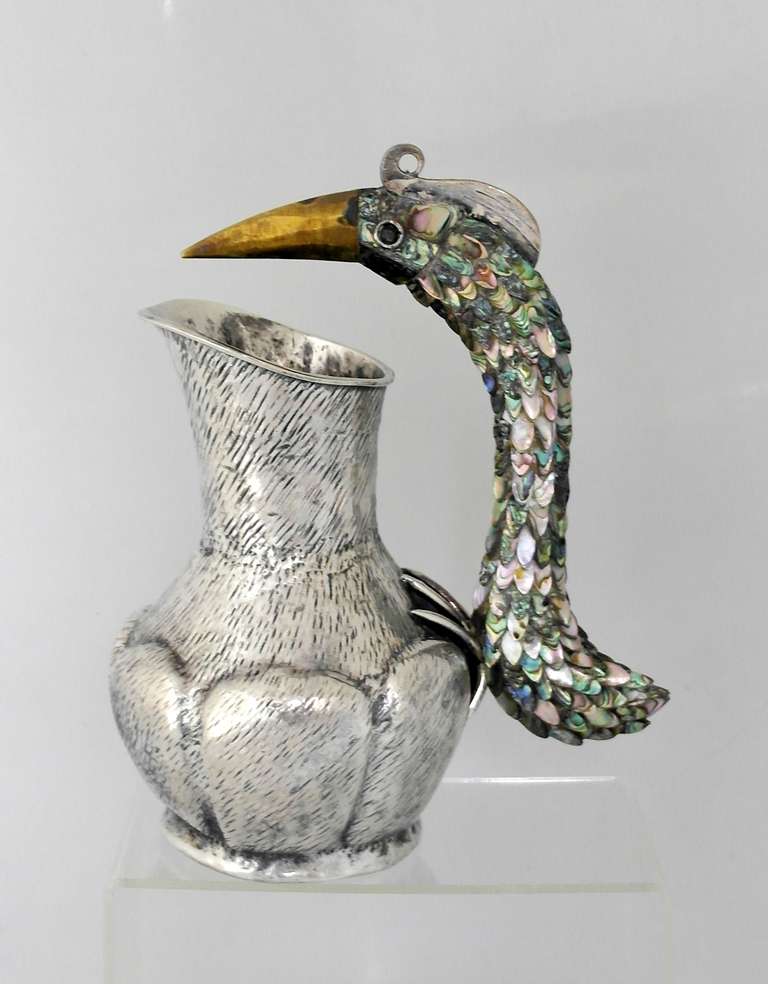 Being offered is a contemporary silverplate pitcher by Los Castillo of Taxco, Mexico. Entirely handmade piece with unusual texture; an exotic bird handle with abalone feathered inlay; incredible detail throughout, including the feet. Dimensions: 10