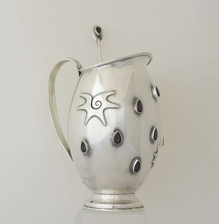 Being offered is a superb circa 1960 sterling silver pitcher by Carmen Beckmann of Taxco, Mexico, superb modernist design, bulbous form with large bezel set amethysts and applied conch shells; includes the stirrer which also bears large amethyst