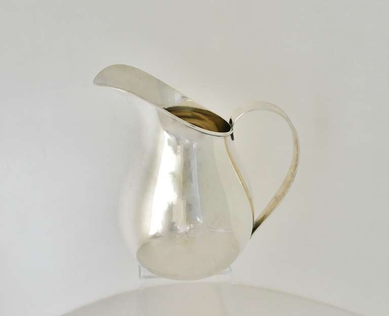 Being offered is a circa 1960 hand made sterling silver pitcher by Allan Adler of Los Angeles, California, the body is bulbous shaped and features an elegant, oversized spout, with applied handle.  Dimensions 8 inches tall by 9 inches across handle.