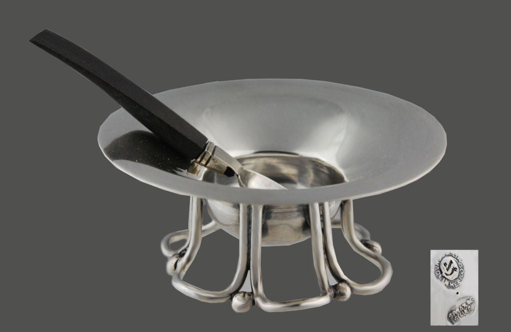 Being offered is a fine pair of circa 1955 sterling silver condiment or master salt cellars by William Spratling, of Taxco, Mexico, the cellars with a long everted lip atop spirals of silver, the spoons (with rosewood handles) and bowls large enough