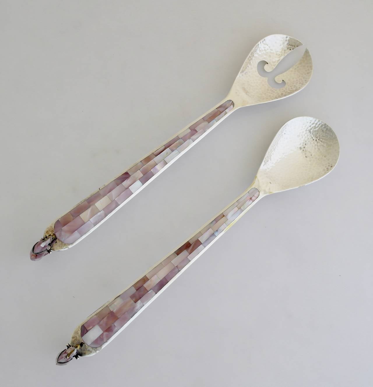 Being offered are a pair of salad servers by Los Castillo of Taxco, Mexico; large handwrought set with mother of pearl inlay  and a figural parrot at the terminus. Dimensions: 13 1/2 inches long.  Marked as illustrated.  In excellent condition.