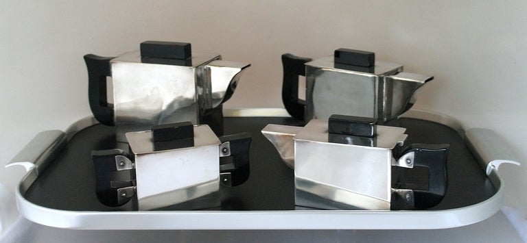 Being offered is a silverplate coffee and tea service, cubist design with geometric nickel silverplated bodies including a coffee pot, tea pot, sugar and creamer, accompanied by an unrelated serving tray. Dimensions: coffee pot 4 inches height x 9