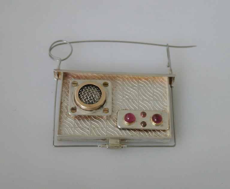 Description:  Being offered is contemporary sculptural radio brooch, by Chris Darway, of Lambertville, New Jersey, the textured sterling silver rectangle suspending from an exposed wire pin frame, decorated with various metalcomponents, including a