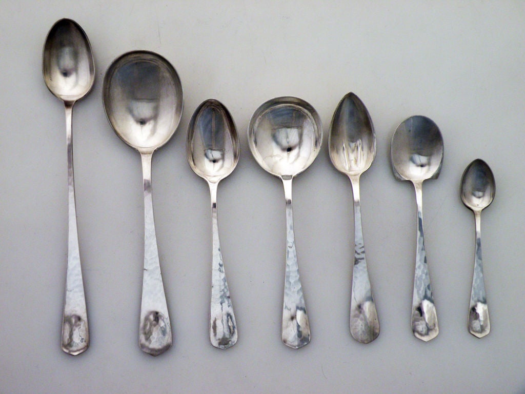 Being offered is a fine and large 184 piece set of circa 1925-1931 handwrought sterling silver flatware by Lebolt, of Chicago, IL, in a moderne arts and crafts motif, each piece handhammered.  The terminus of each stem has a raised oblong, gourdlike