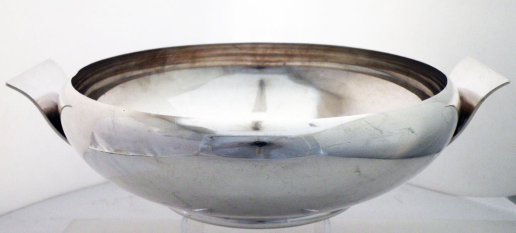 Being offered is a fine and large circa 1950 modernist sterling silver centerpiece bowl by Allan Adler of Los Angeles, CA, of elegant and moderne design, with applied undulating handles, all raised on an elevated pedestable base.  Marked as