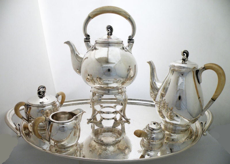 Being offered is a fine circa 1945 sterling silver tea - coffee set with tray by Holger Rasmussen, of Denmark, comprising a tea kettle, coffee pot, creamer and covered sugar bowl, burner stand, burner and 2-handled tray, each marked and with