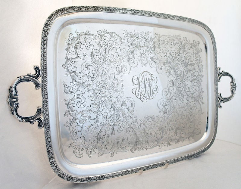 Being offered is a fine and large circa 1845 coin silver tray by William Adams, of New York, the surface engraved in a rococo motif, a swirl of flowing forms, with an applied die rolled border/rim, with applied, cast handles, all standing on four