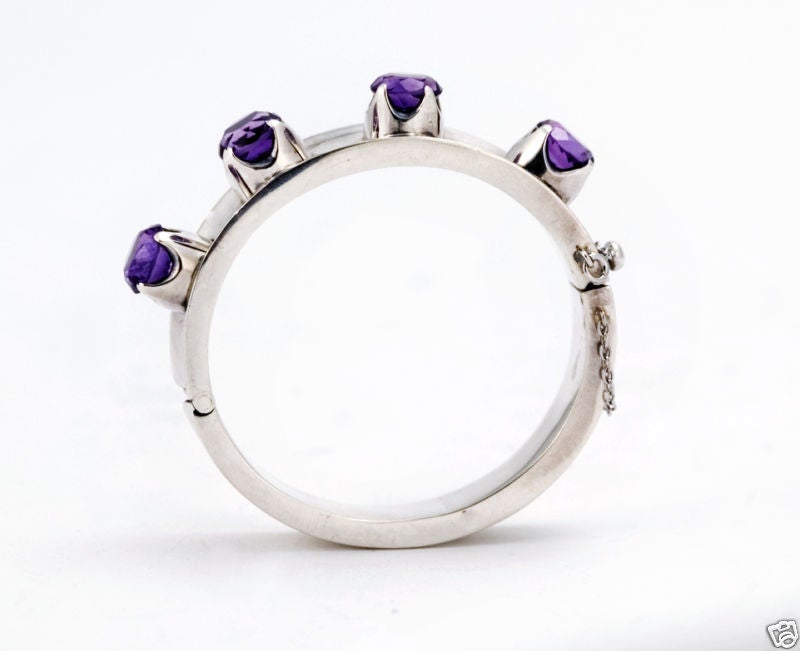 Being offered is a fine circa 1960 sterling silver and amethyst bracelet by Los Ballesteros, of Taxco, Mexico, a concave sterling silver bangle bracelet set with four (4) large amethysts, the bracelet with a chain safety clasp  Dimensions:  bracelet