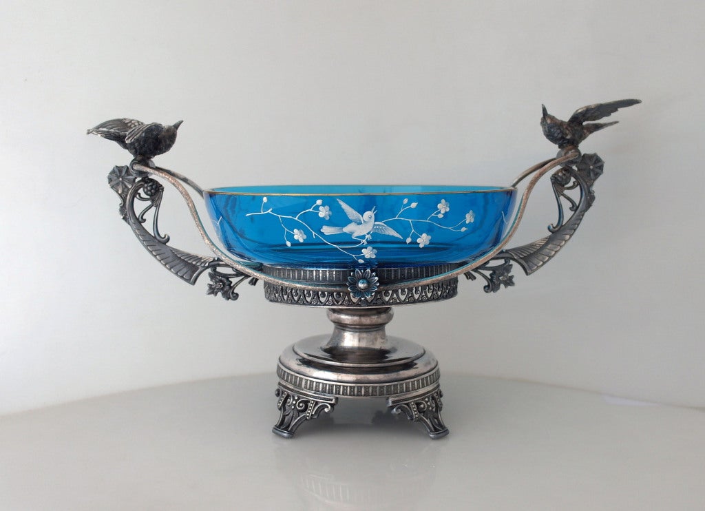 Being offered is a museum quality circa 1880 silverplate bride's basket centerpiece by Aurora Silver Company, of Aurora, IL, the pedestal holder pierced with Japanesque accents, the handles bearing two three-dimensional hummingbirds, all standing on