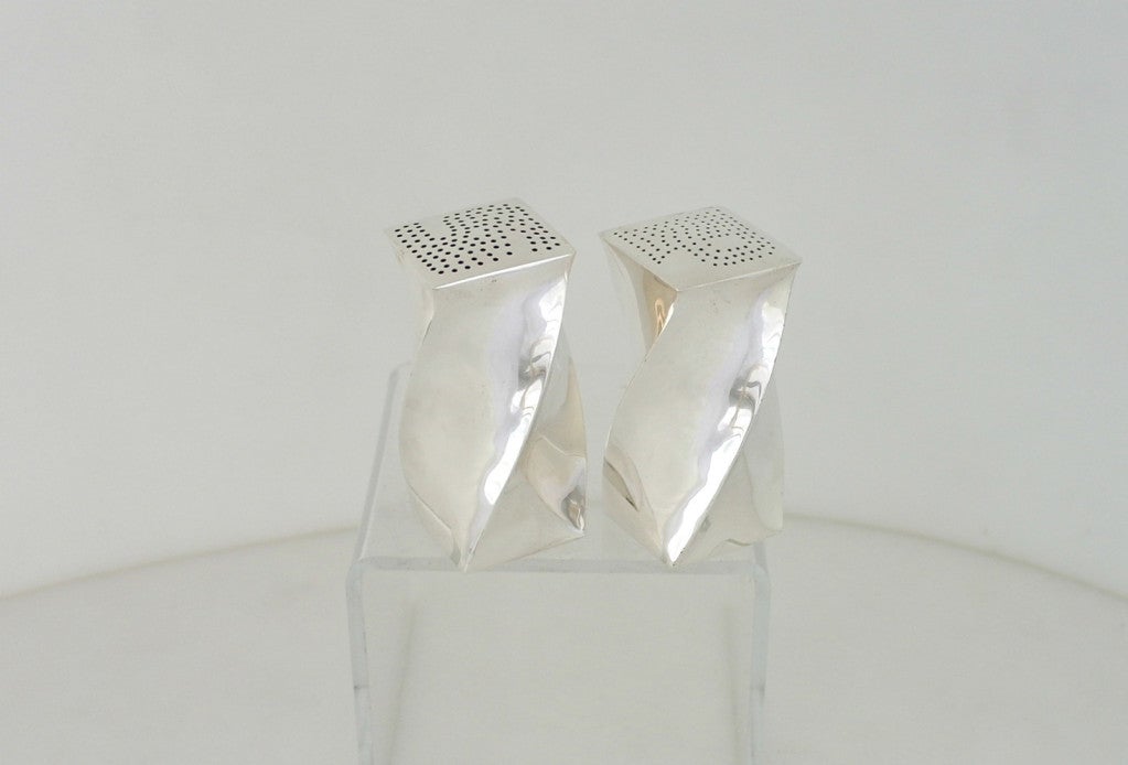 Being offered is a rare pair of circa 1955 sterling silver salt and pepper shakers by Antonio Pineda, of Taxco, Mexico, in a modern geometric design, the body of each shaker marvelously twisted to create a celestial swirl. Dimensions 3 1/8 inches